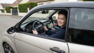 Jeune adolescent souriant au volant d'une voiture sans permis
