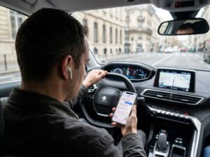 Conducteur au volant utilisant son téléphone et portant des écouteurs